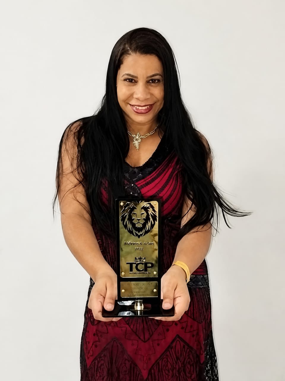 Karine Ferreira sorrindo, segurando o troféu do prêmio Mérito & Ação